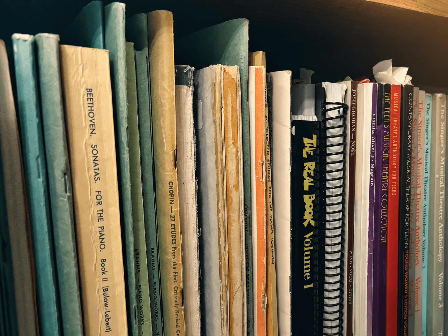 Upright music books arranged on a studio shelf